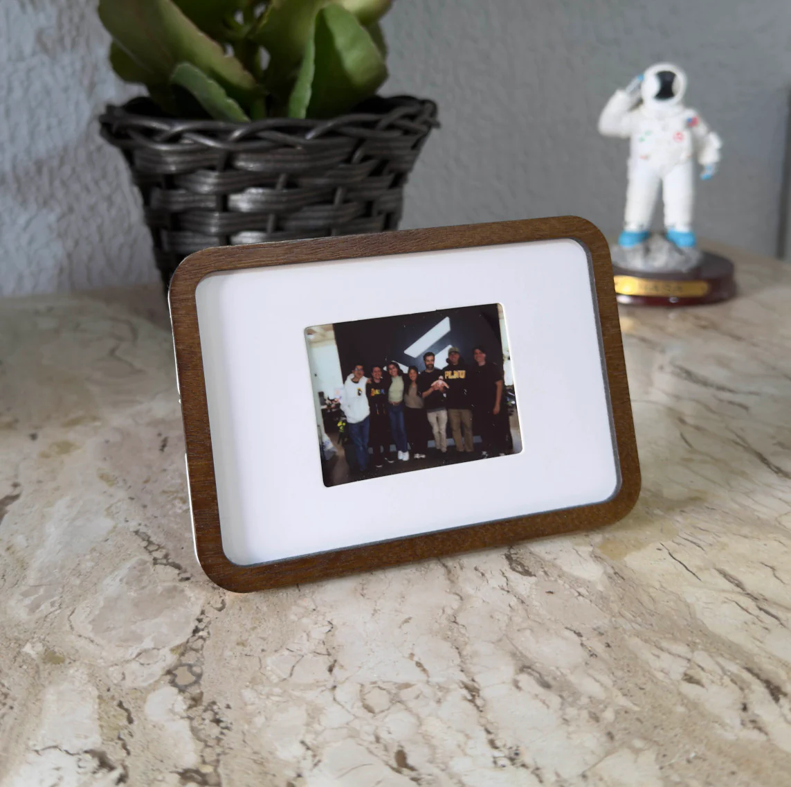 Pop-up Frame on a stone table holding an instant photo of a group of friends